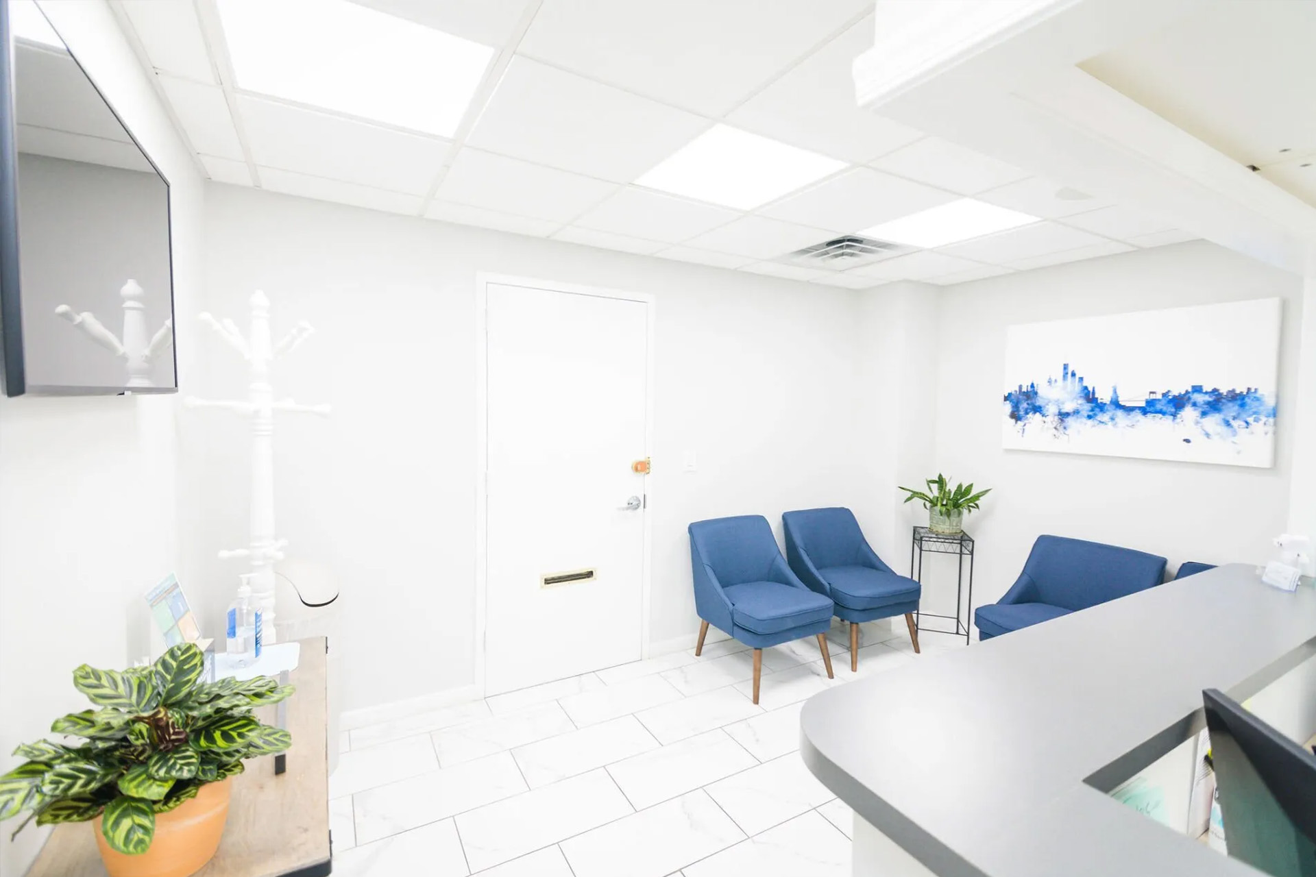 An interior view of a modern, well-lit dental office with a reception area featuring a desk and chairs.