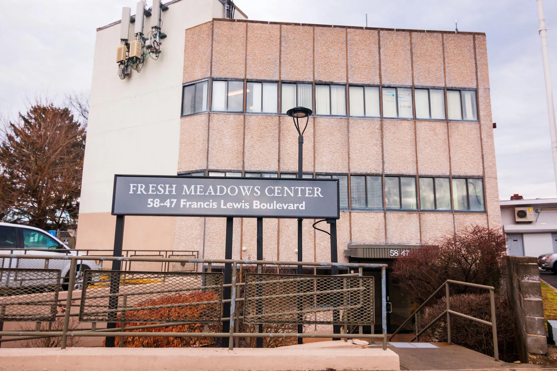 The image shows a sign for Fresh Meadow Center, which is likely a community or cultural center, with a building in the background.