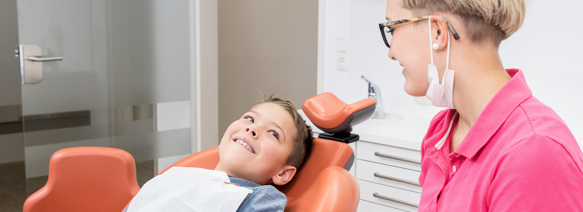 A woman and a child in a dental office, with the child seated in a dental chair.