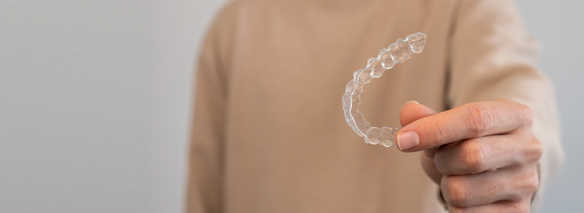 Hand holding a transparent bubble with soap inside, against a blurred background.