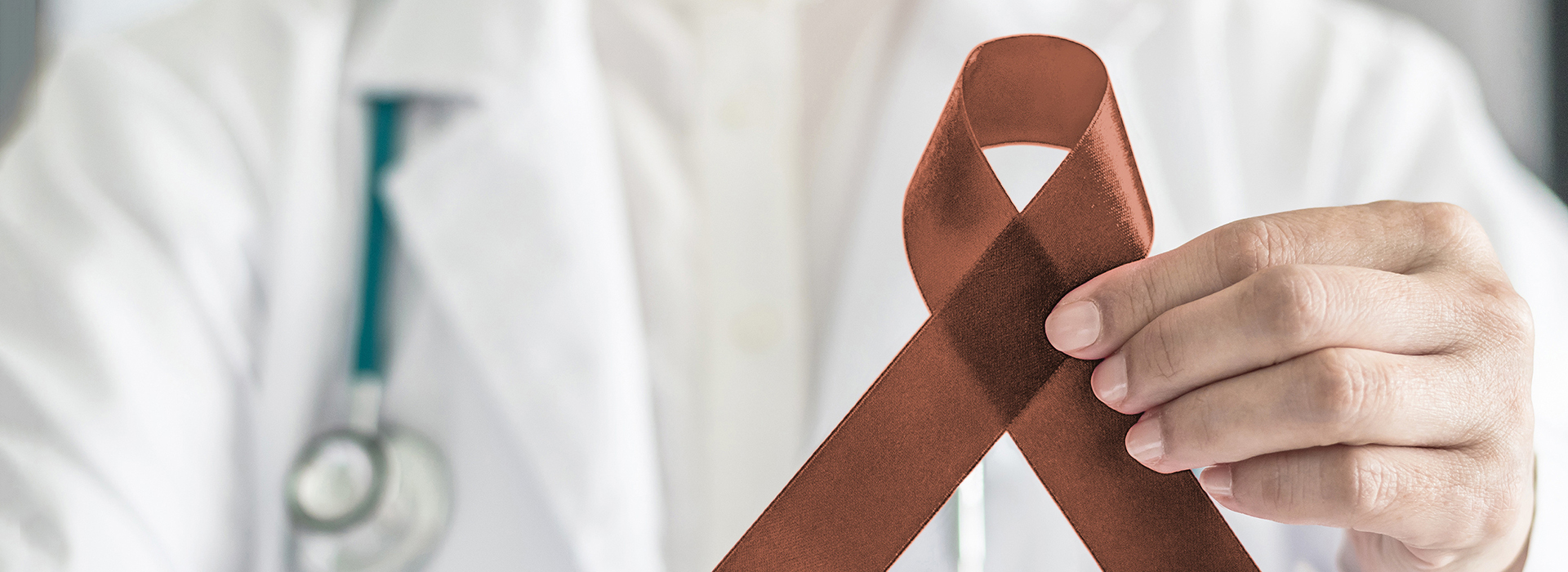 The image features a healthcare professional holding up a red ribbon with a brown bow, symbolizing awareness for a specific cause.