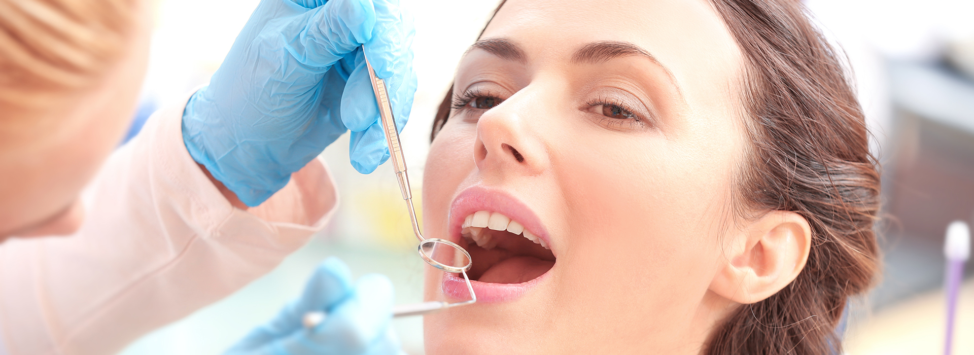 A woman receiving dental care, with a dental professional performing a procedure on her teeth.