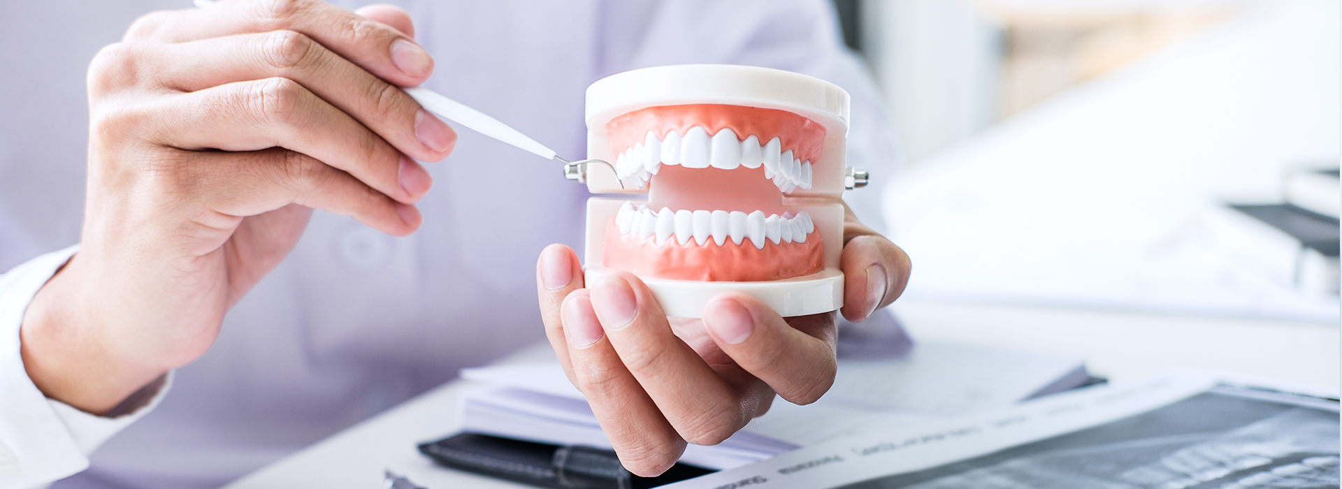 A person holding a toothbrush with their teeth visible, wearing a face mask and working at a desk.