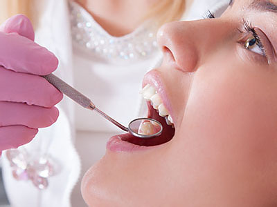 A dental professional is performing a procedure on a patient s mouth, with the patient seated and wearing protective gloves.