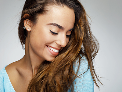 A young woman with long hair, smiling and looking to her left.