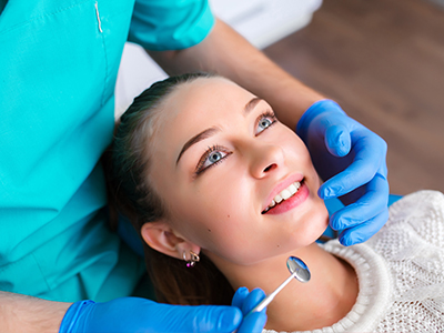 A dental professional is performing a procedure on a patient s teeth, with the patient smiling and appearing relaxed.