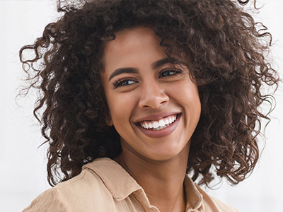 Woman with curly hair, smiling and looking directly at the camera.